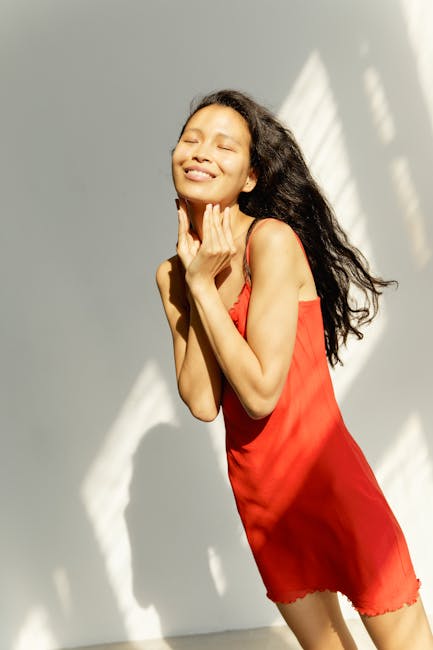 Smiling woman in a bright room doing a simple neck stretch.